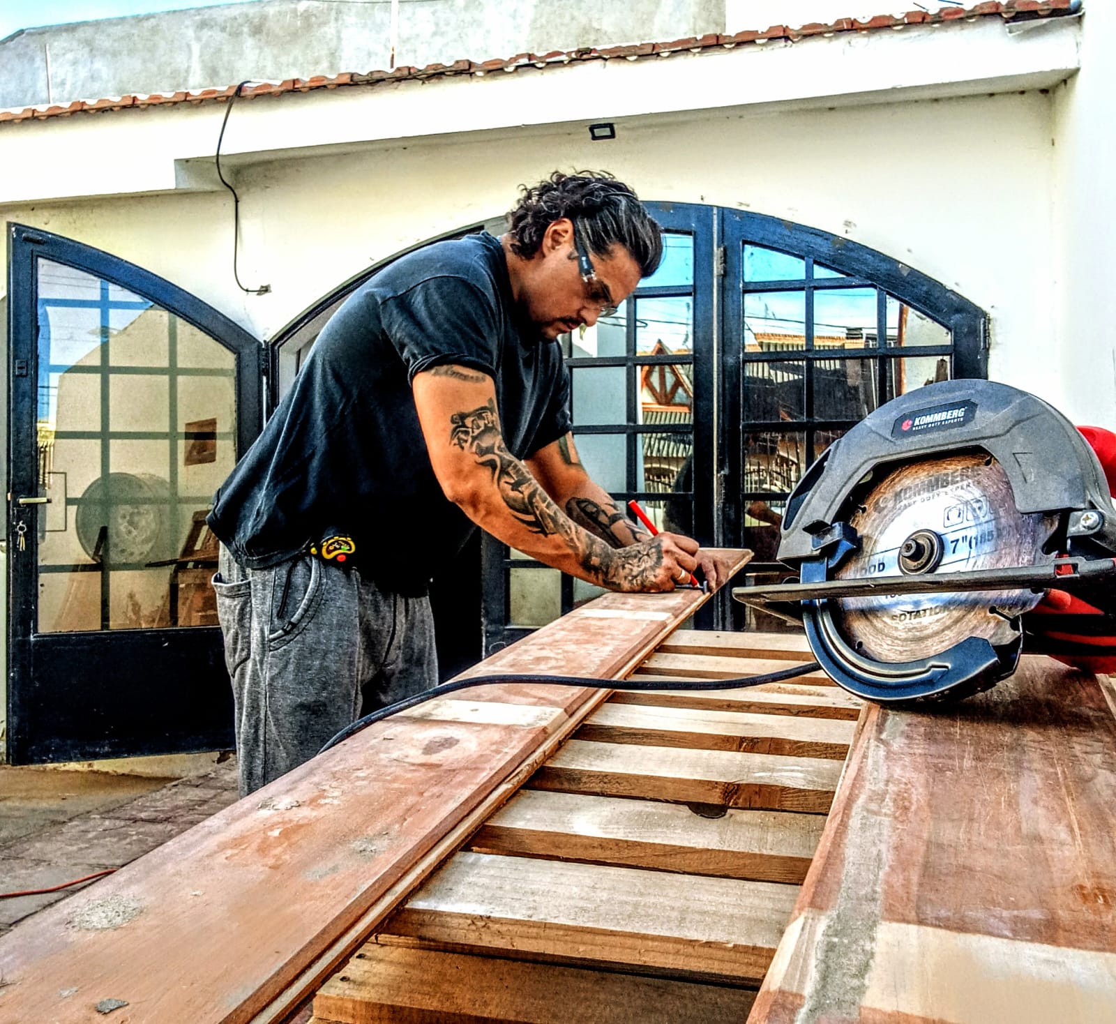 Mauricio midiendo y cortando tablones de madera recuperada con sierra circular